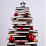 books stacked in a holiday tree shape and decorated with red balls and silver star on top